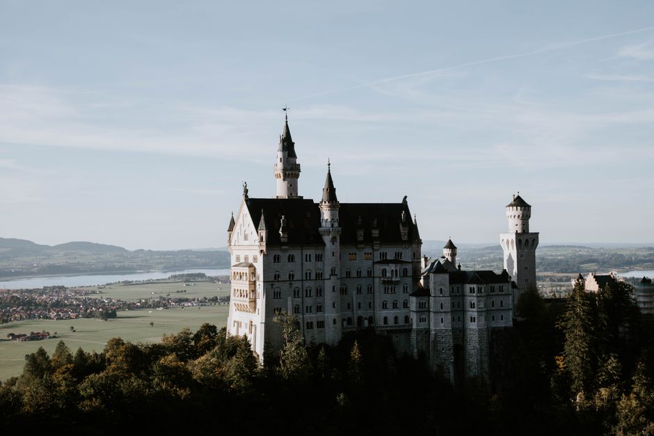Dramatic view of Neuschwanstein Castle surrounded by lush greenery, set in the Bavarian landscape.