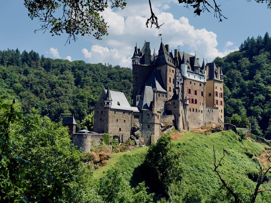 Eltz Castle stands majestically amidst lush green forests in Wierschem, capturing its historic charm on a bright summer day.
